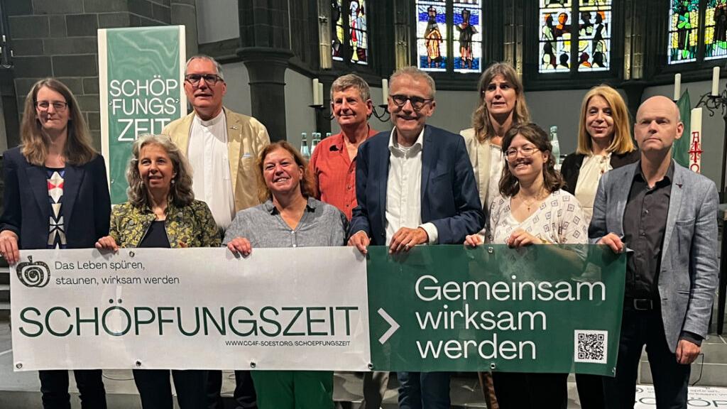 Personen hinter einem Banner der Aktion 'Schöpfungszeit'
