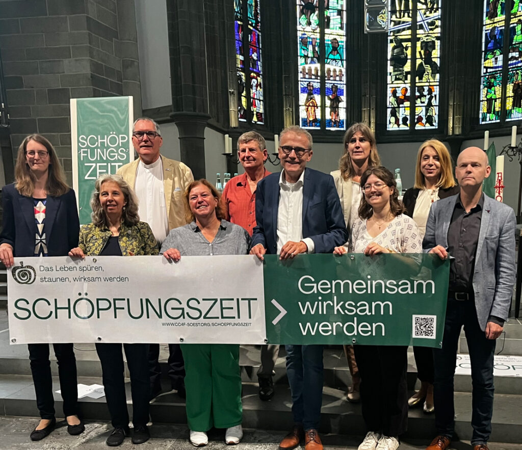 Personen hinter einem Banner der Aktion 'Schöpfungszeit'