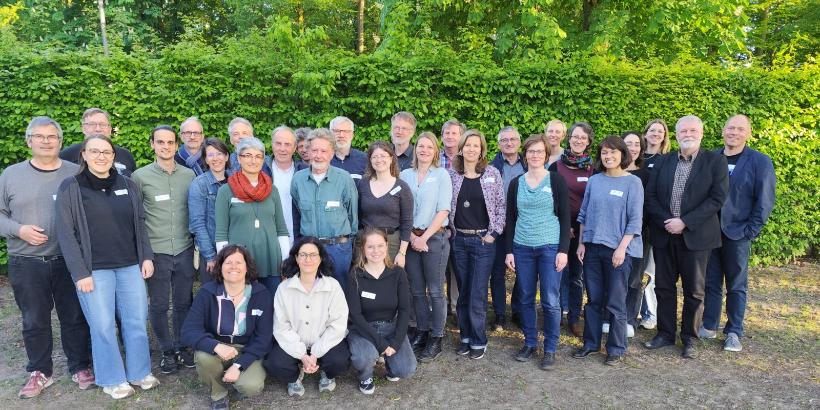 ca 30 Menschen vor einer grünen Hecke