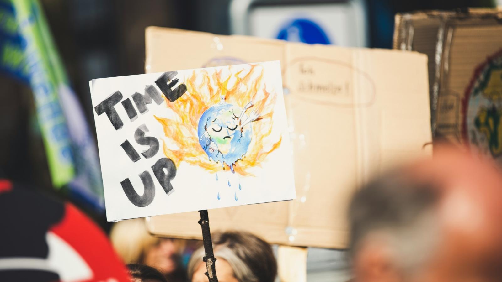 Eine Person auf einer Demo hält ein Schild mit slogan time is up