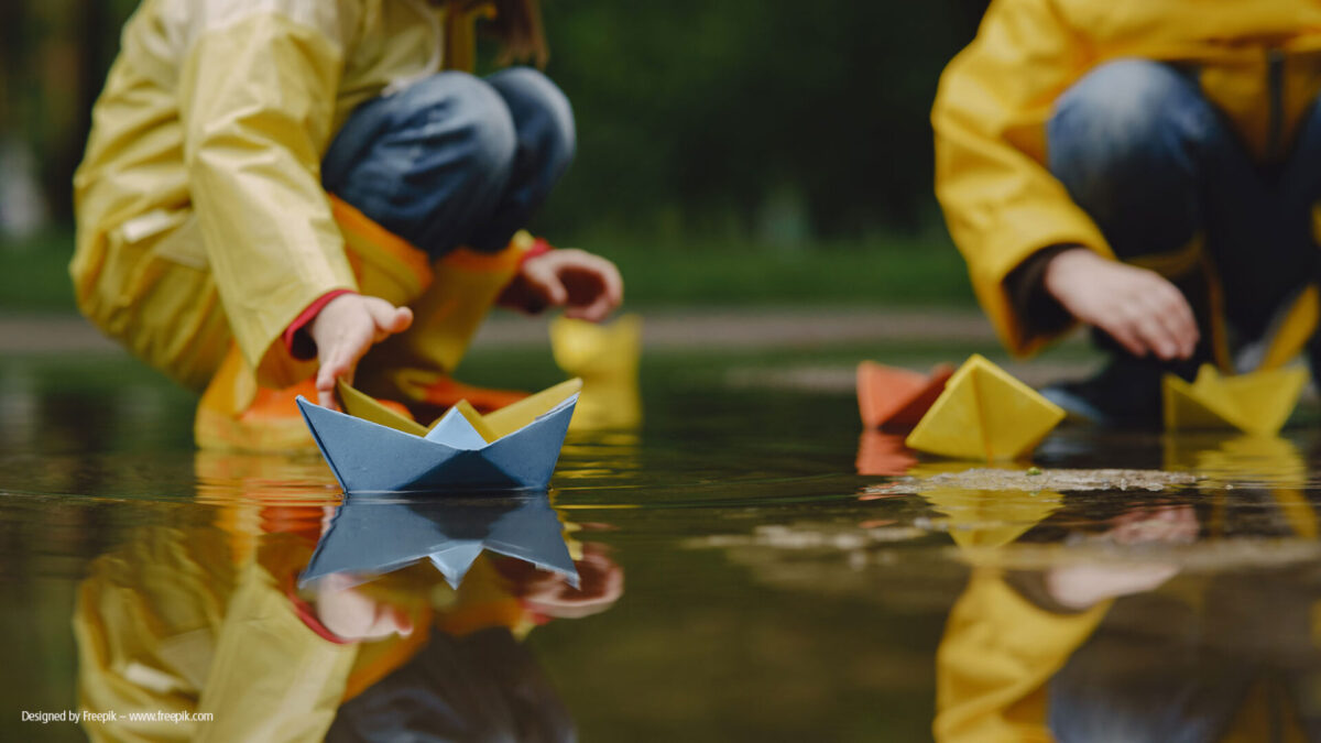 funny-kids-rain-boots-playing-with-paper-ship-by-puddle_2000x1125_freepik-1200x675