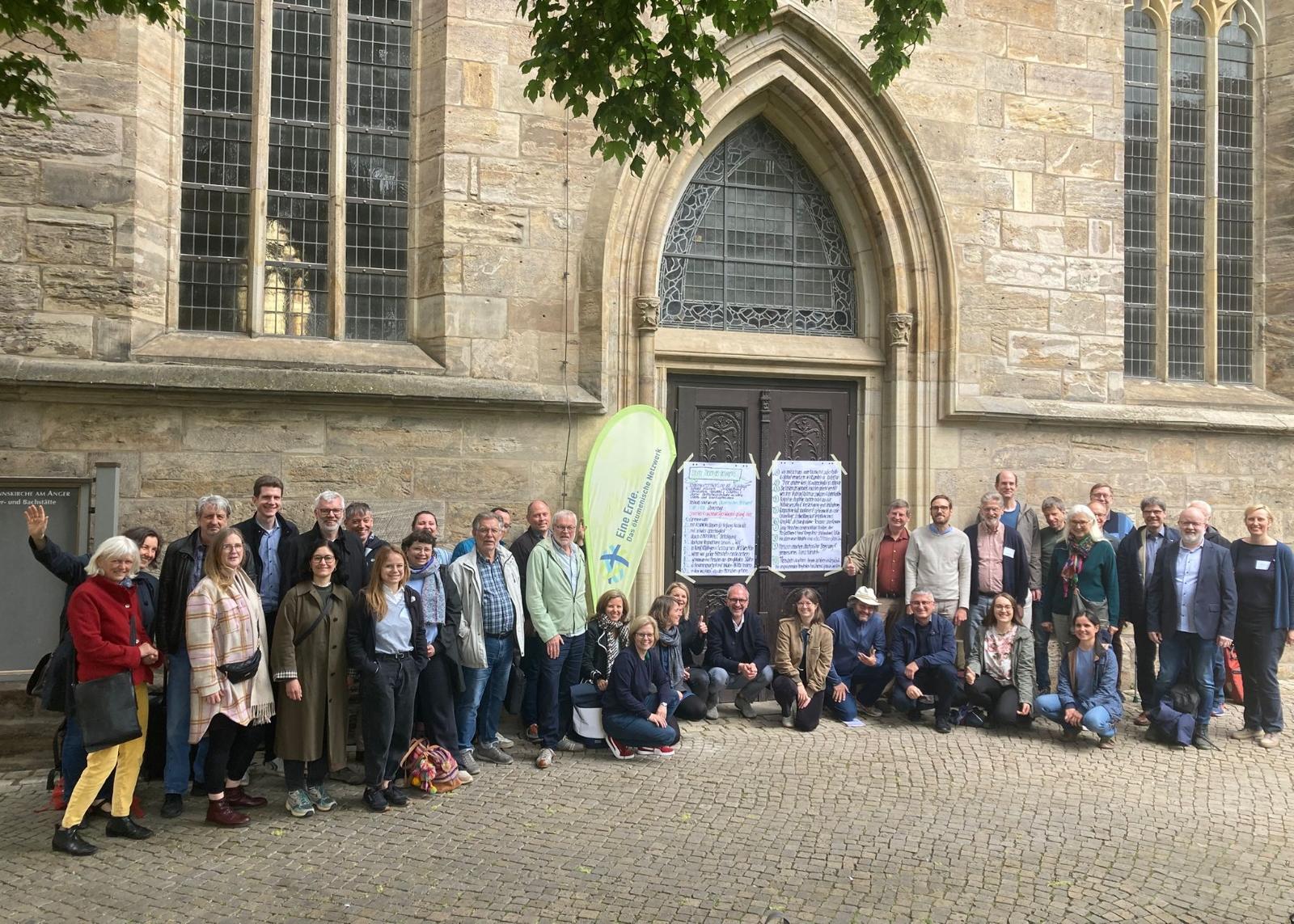 Menschen vor einer Kirche, mit der Beachflag mit dem Logo von Eine Erde