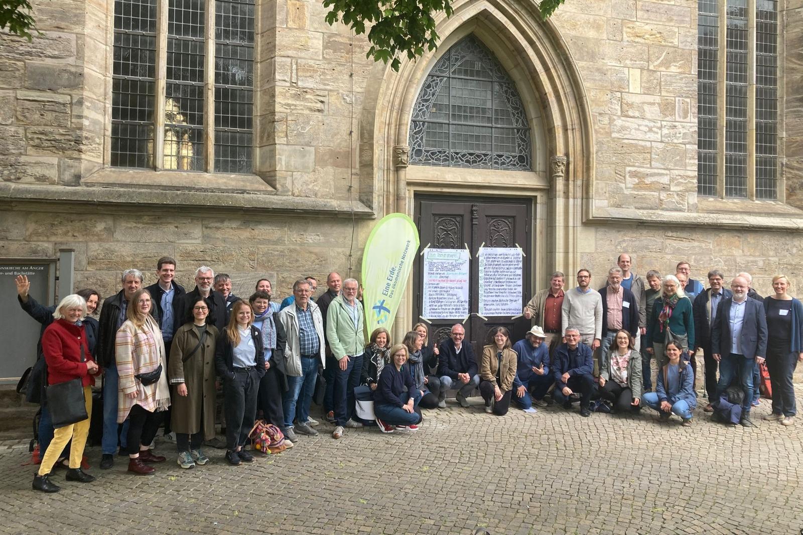 Menschen vor einer Kirche, mit der Beachflag mit dem Logo von Eine Erde