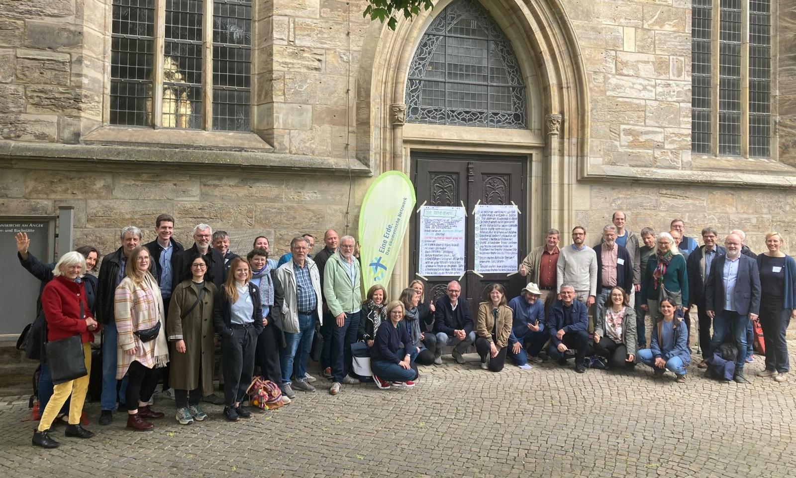 Menschen vor einer Kirche, mit der Beachflag mit dem Logo von Eine Erde