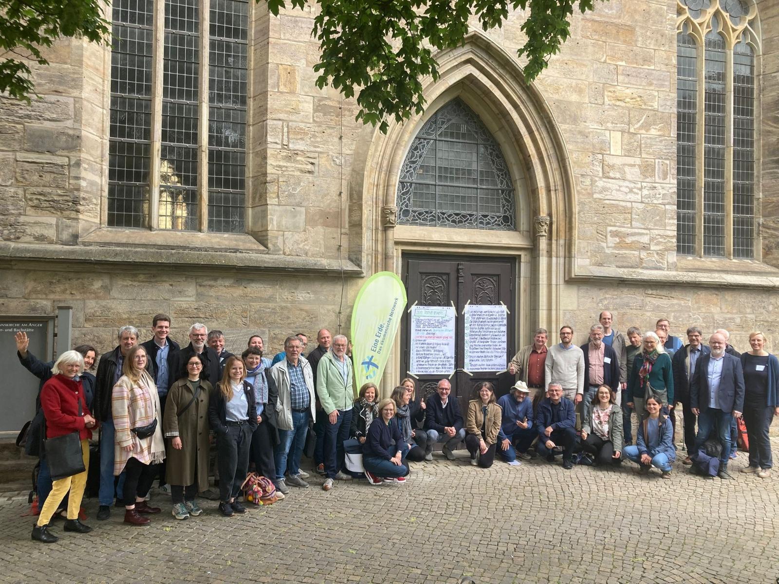 Menschen vor einer Kirche, mit der Beachflag mit dem Logo von Eine Erde