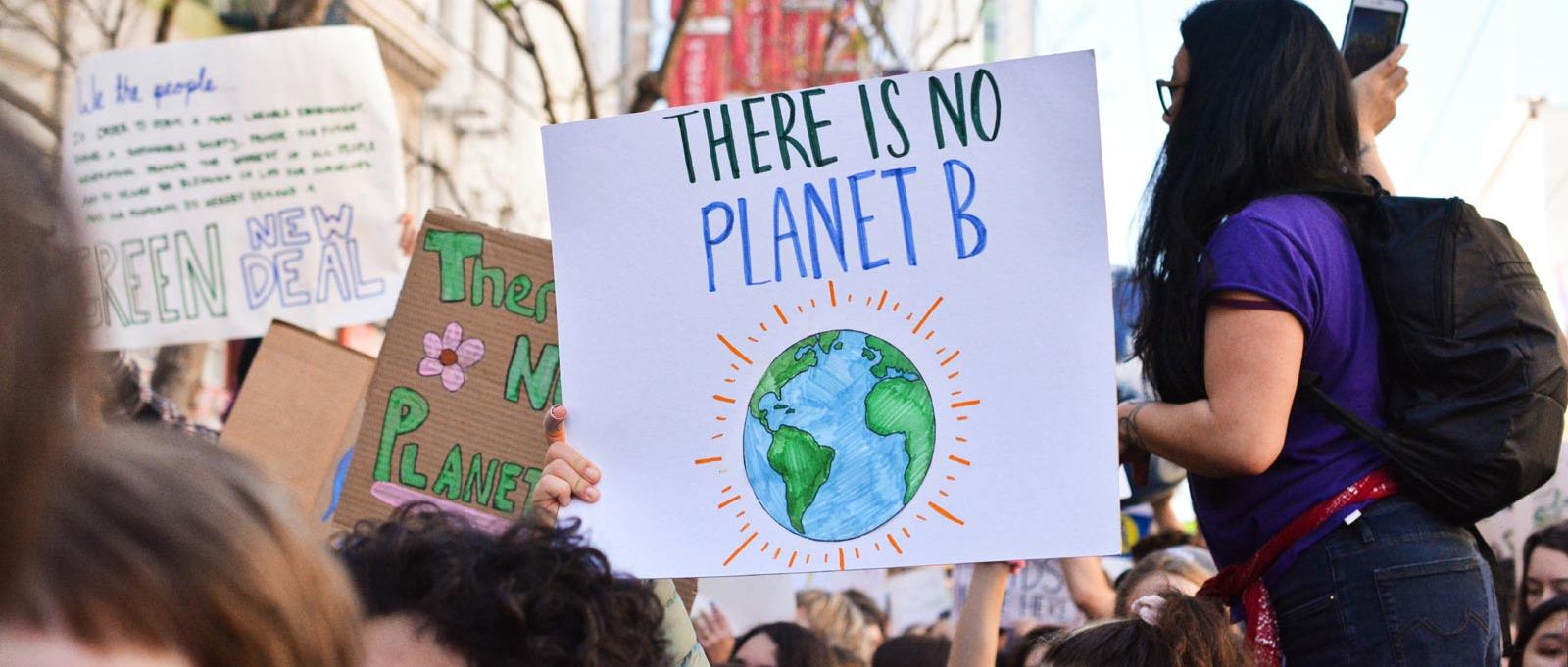 Demonstrierende Menschen halten Schild mit Slogan There is no Planet B