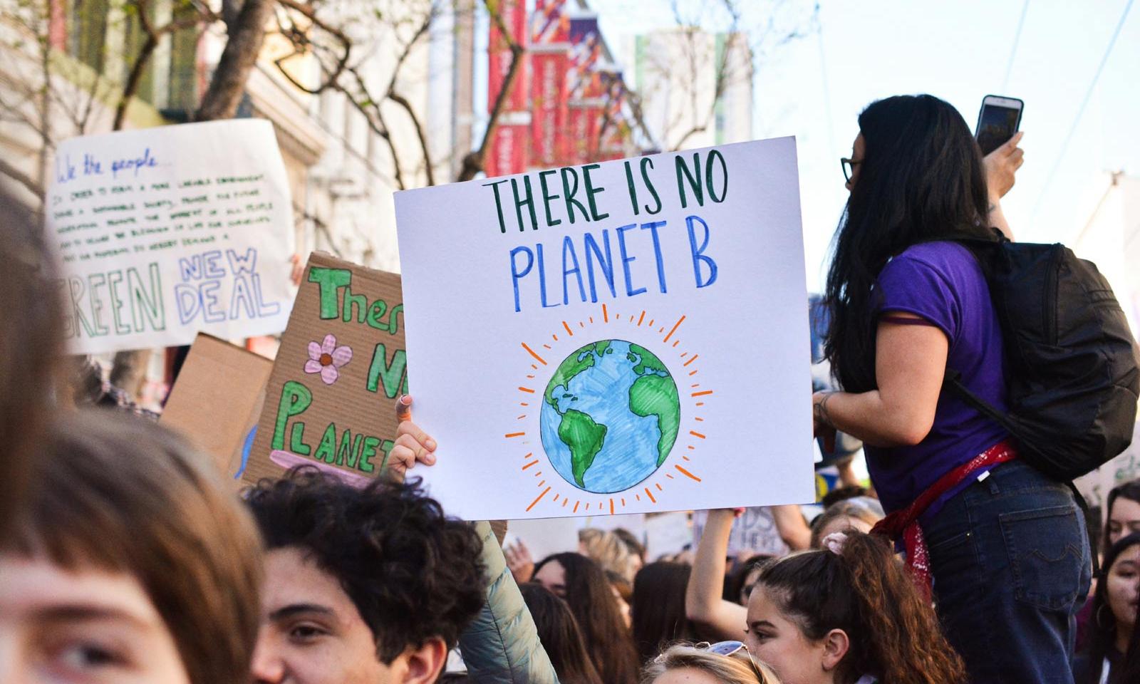 Demonstrierende Menschen halten Schild mit Slogan There is no Planet B