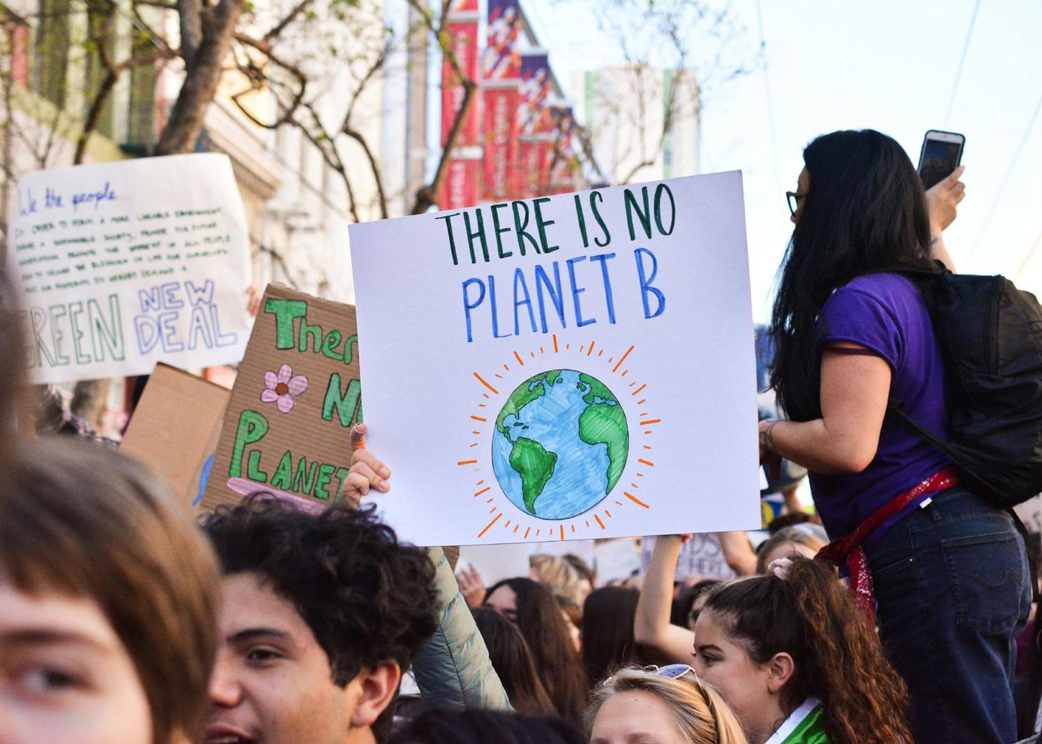 Demonstrierende Menschen halten Schild mit Slogan There is no Planet B