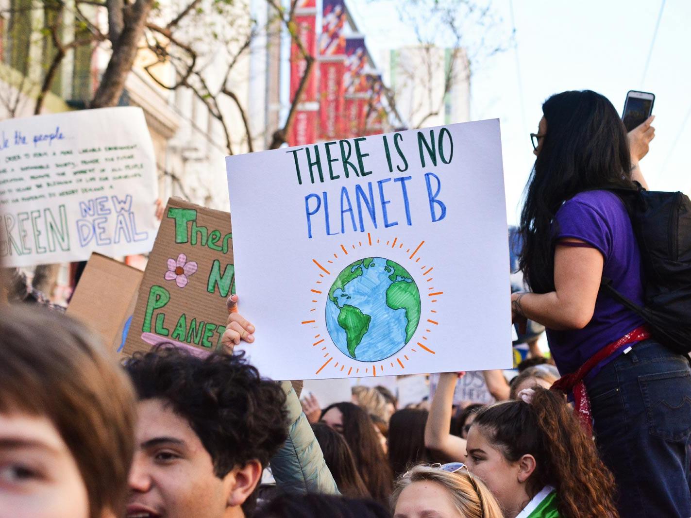 Demonstrierende Menschen halten Schild mit Slogan There is no Planet B