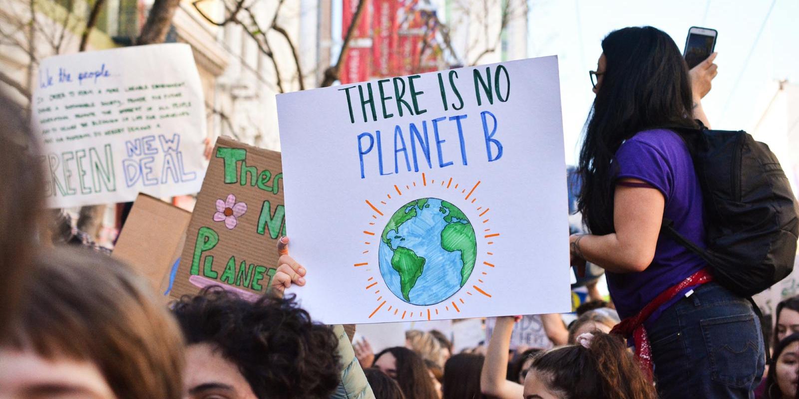 Demonstrierende Menschen halten Schild mit Slogan There is no Planet B